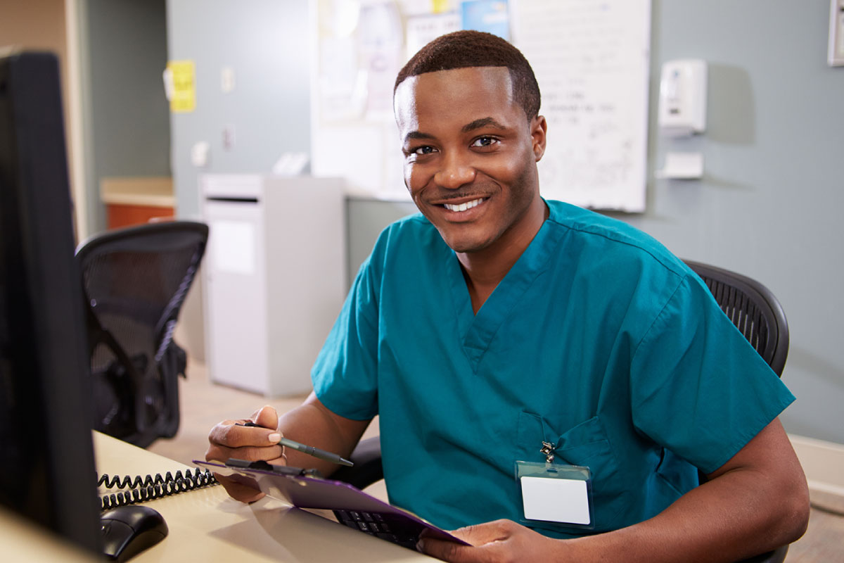male nurse smiling at his desk